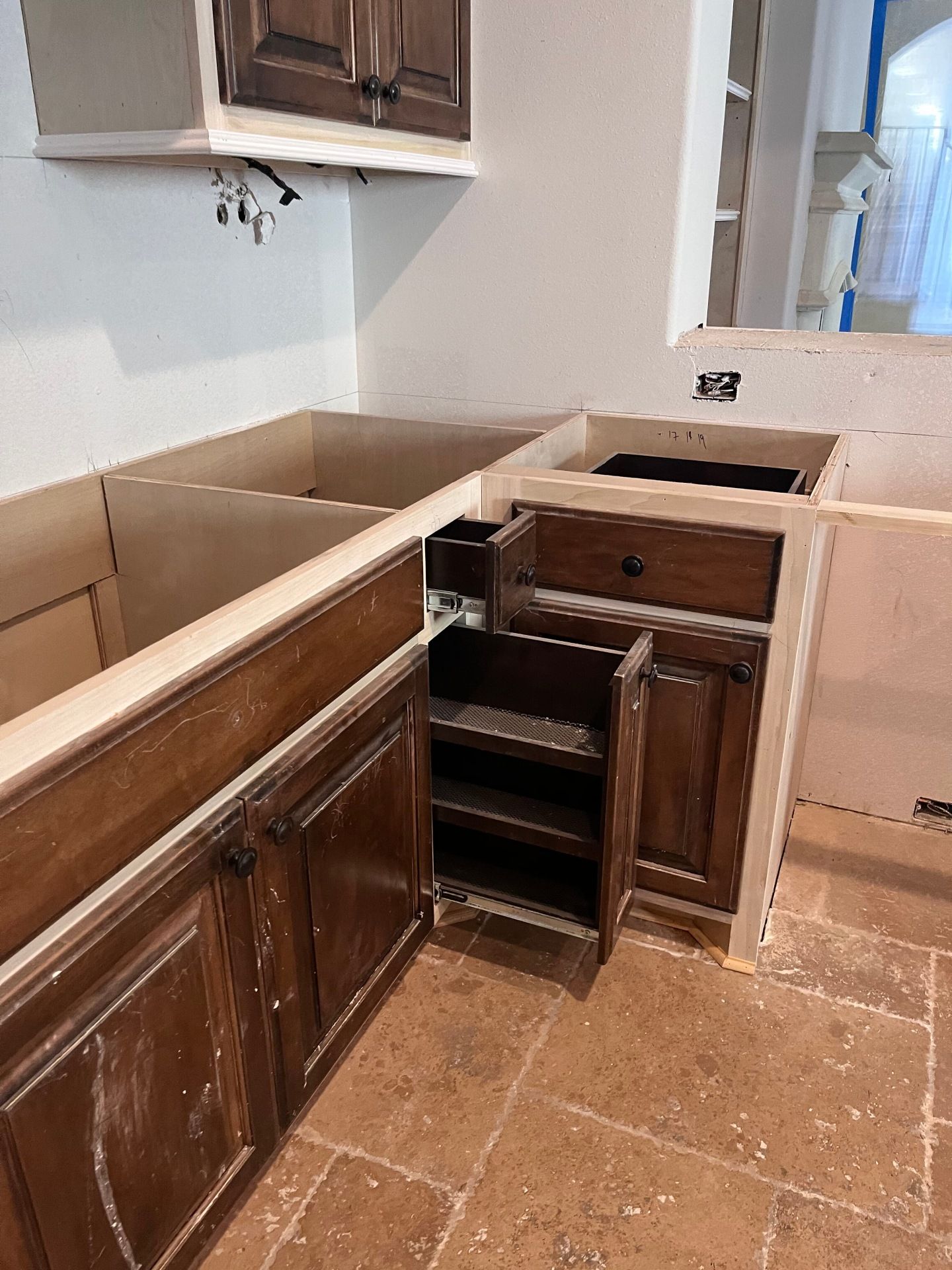 An L-shaped kitchen corner with dark wood cabinets, one featuring an open, pull-out shelving unit on a tiled floor.