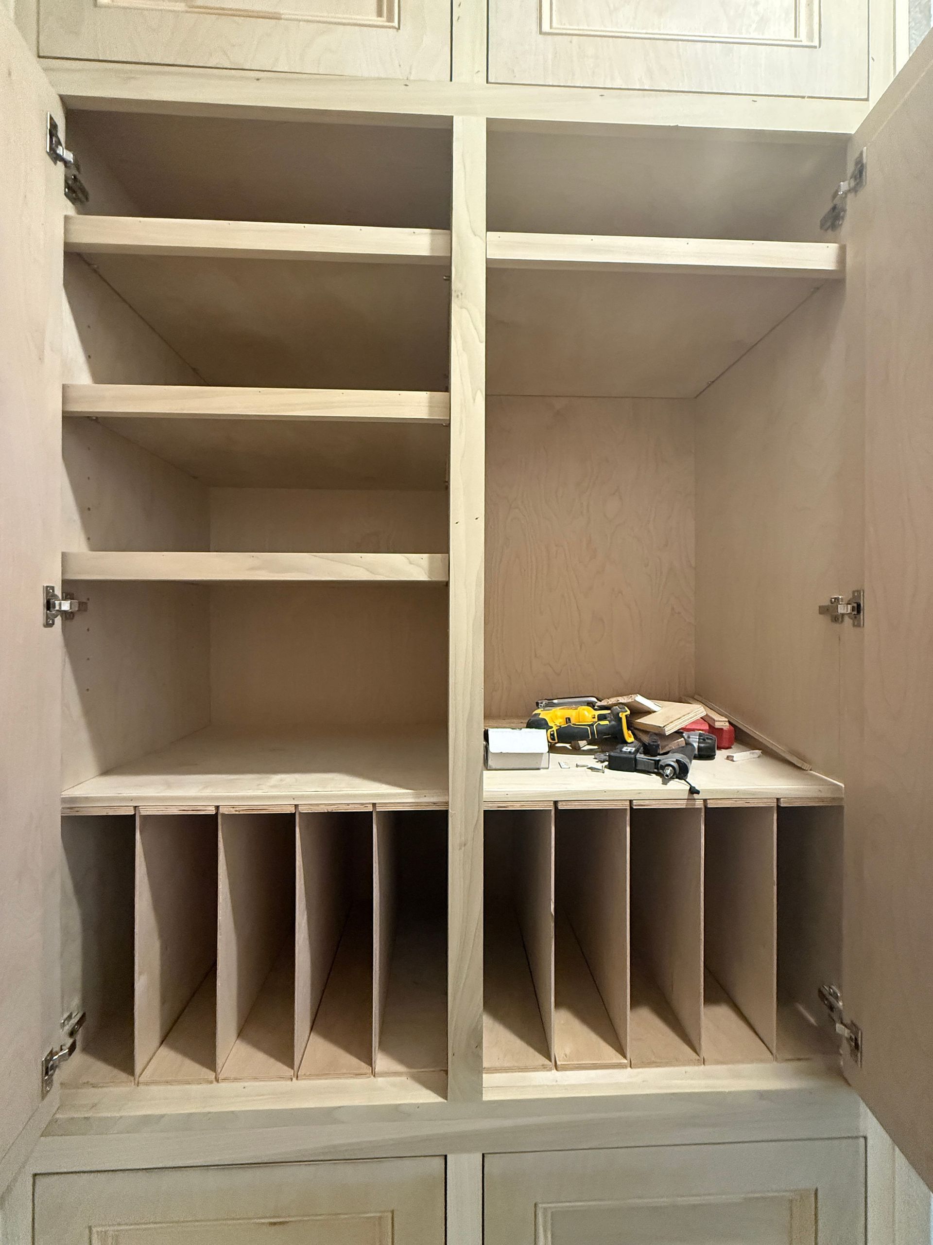 An open wooden storage cabinet featuring horizontal shelving on the left and vertical dividers on the bottom of both sides.
