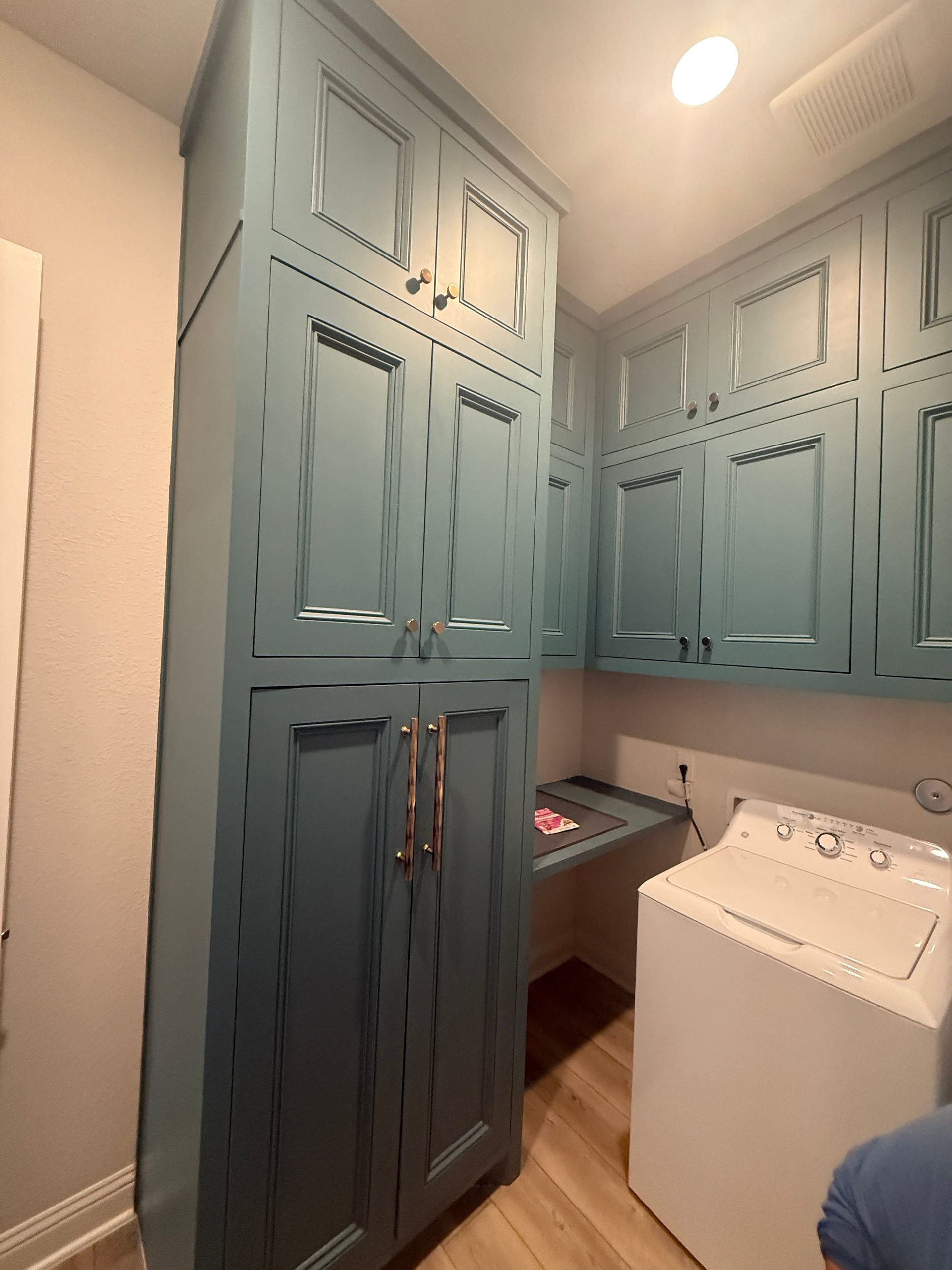 Tall blue cabinets installed in a laundry room next to a white washing machine and a folding counter.