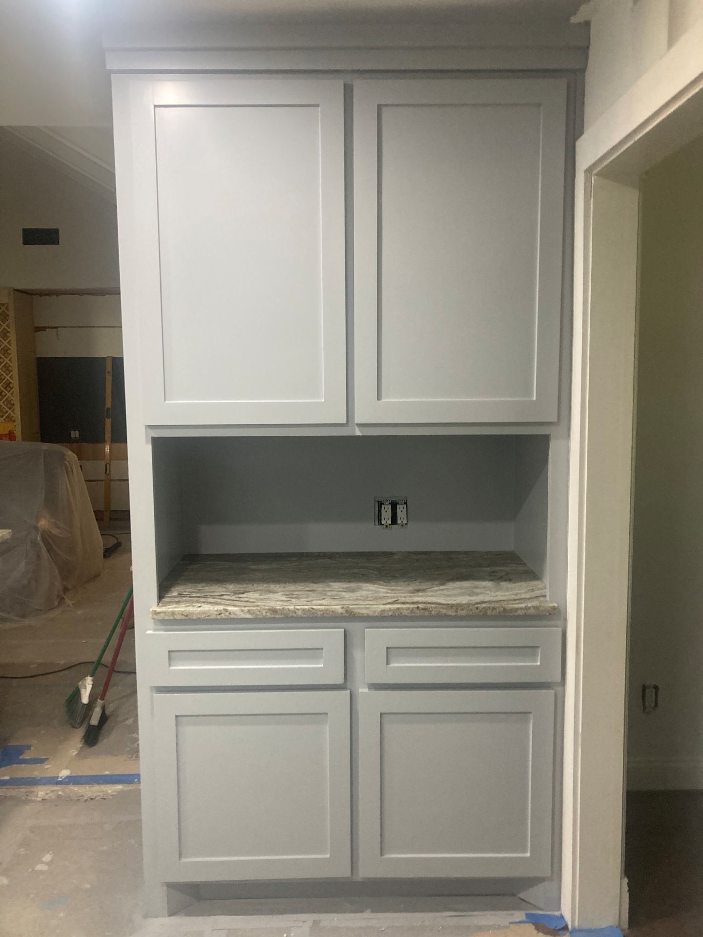 Light gray shaker-style cabinetry with granite countertop, installed in a home with unfinished flooring.