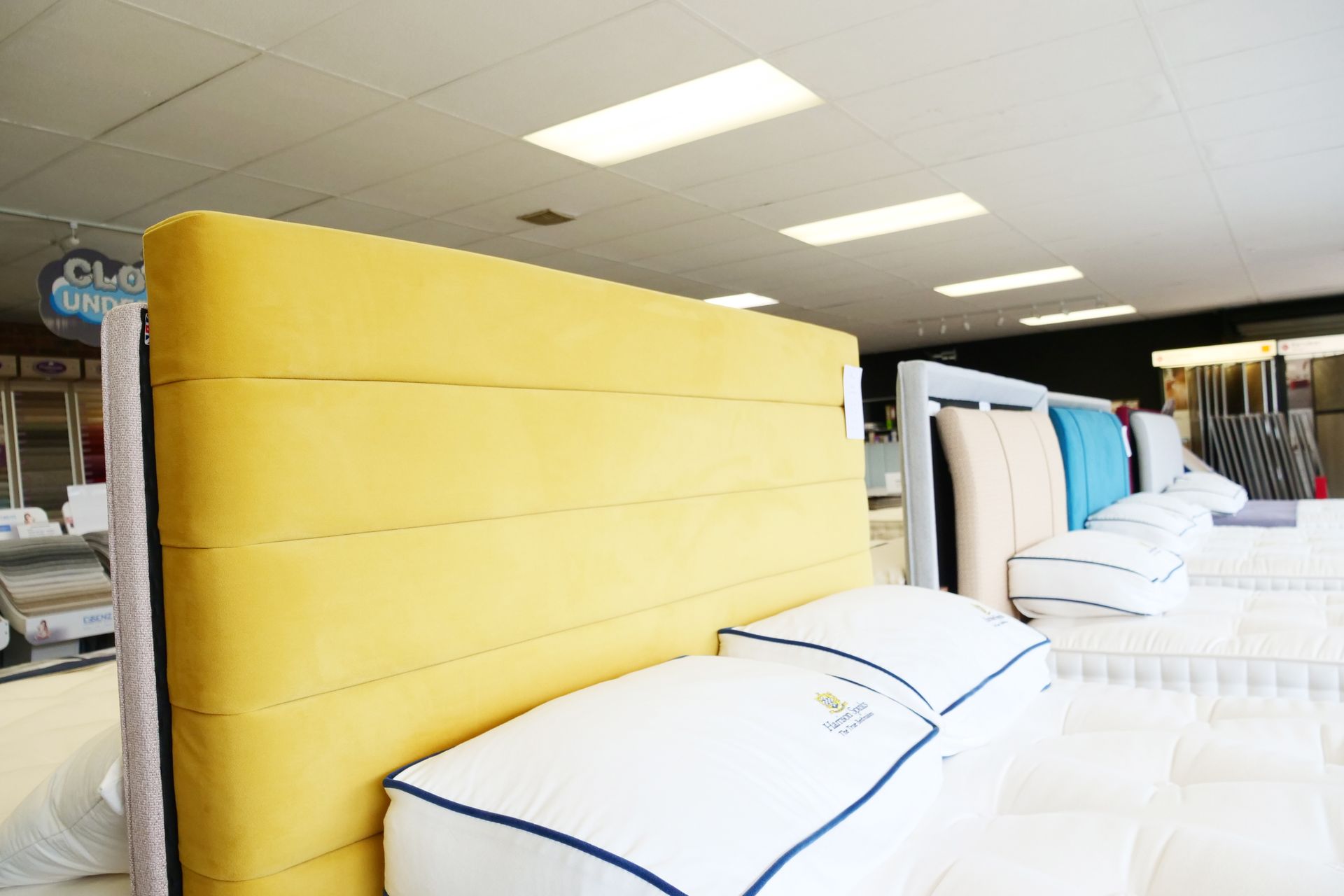 A yellow headboard is sitting on top of a bed in a store.
