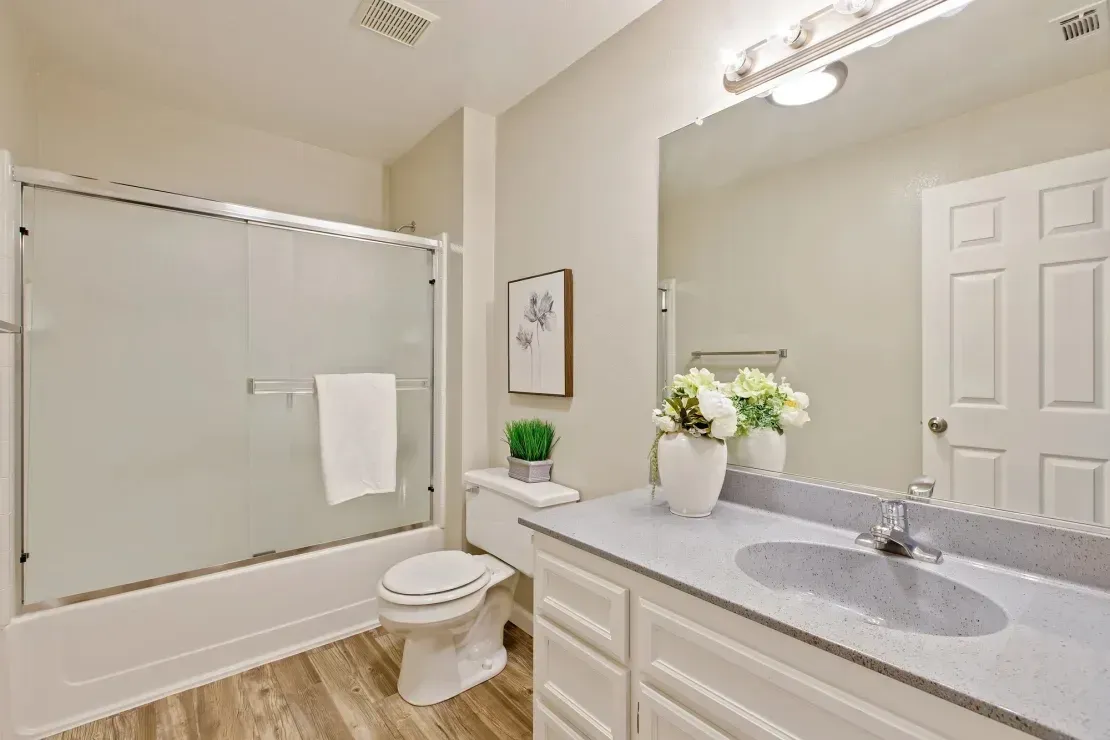 Modern bathroom with a bathtub, toilet, and vanity with a granite countertop.