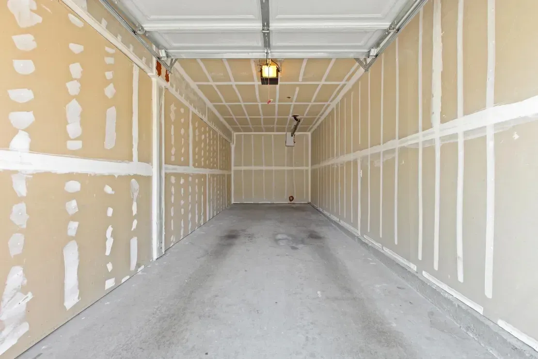 Empty garage with unfinished drywall and concrete floor