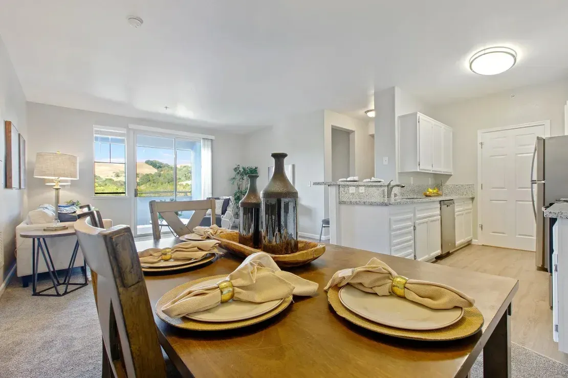 Dining area with a table set for four, leading into a kitchen and living room.