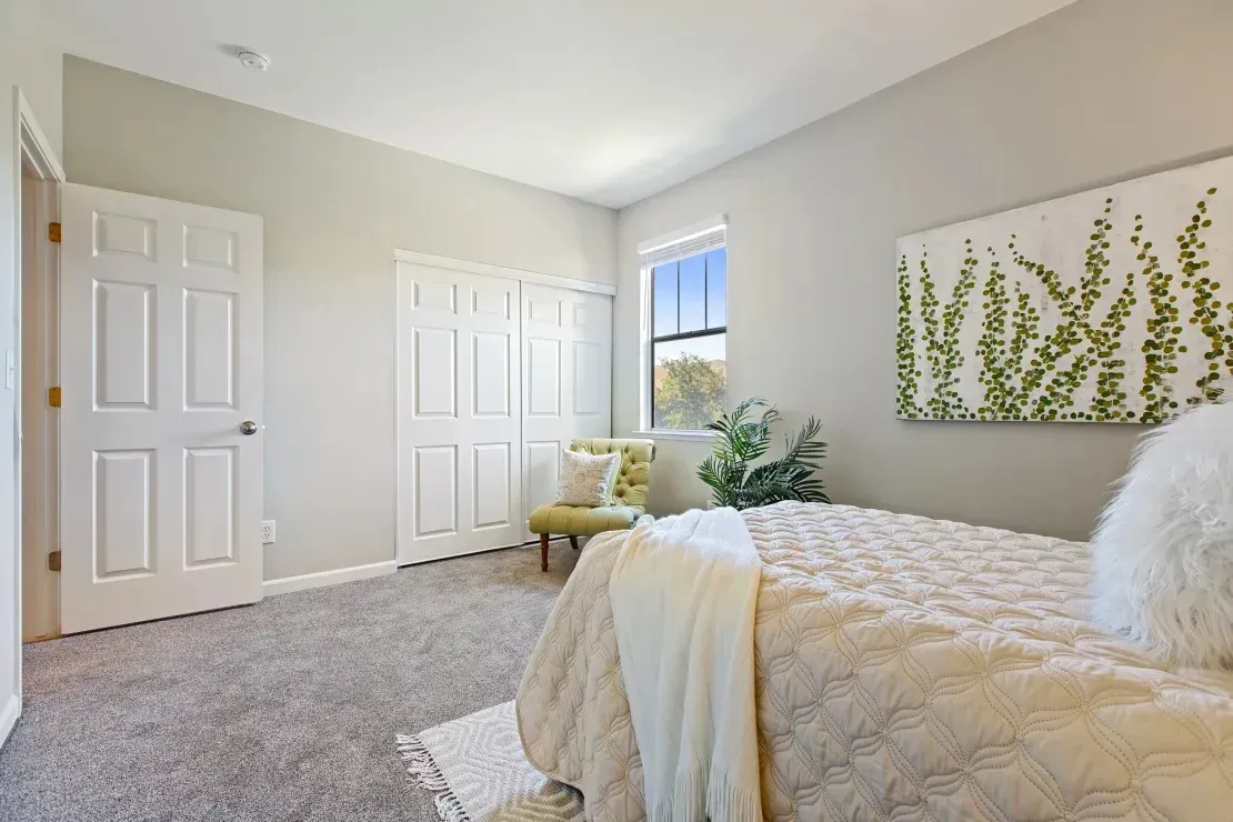 Bedroom with a bed, closet, chair, and artwork.