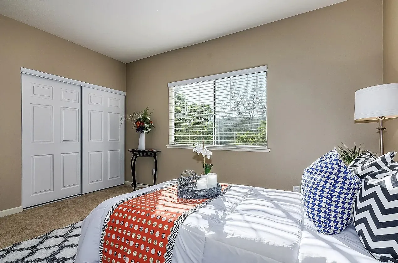 Bedroom with large closet and window overlooking trees.