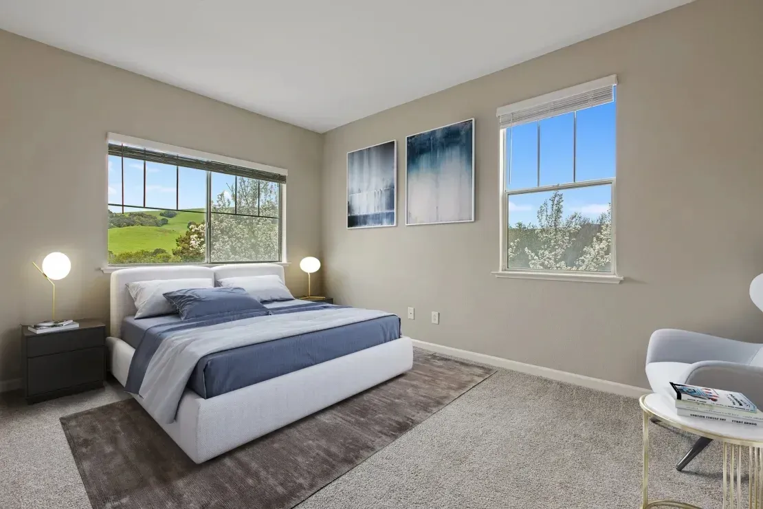 Bedroom with a large bed, two windows with scenic views, and modern decor.