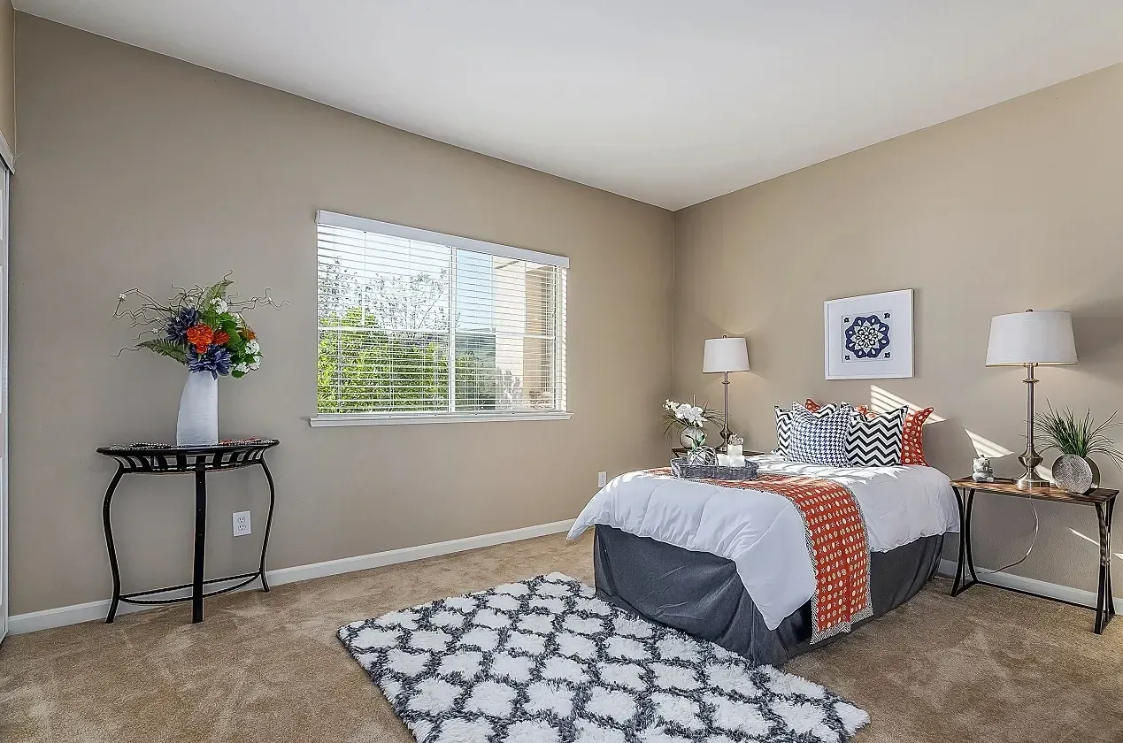 Bedroom with a queen-size bed, accent rug, and a window.