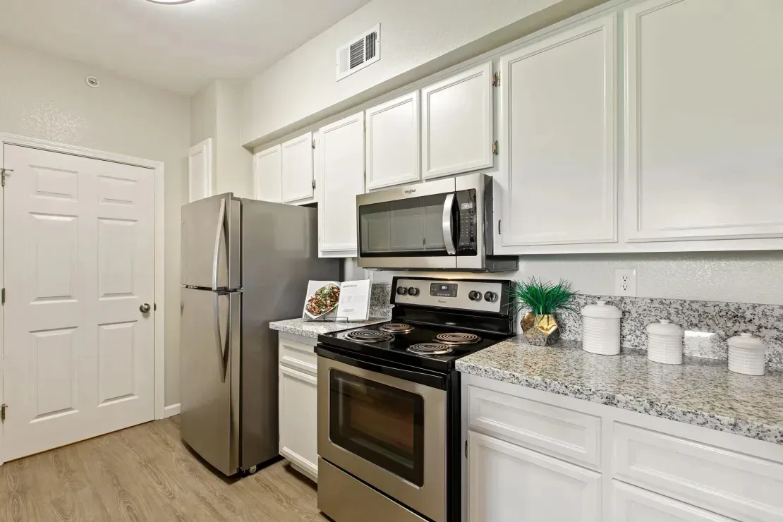 Modern kitchen with stainless steel appliances, white cabinets, and granite countertops.