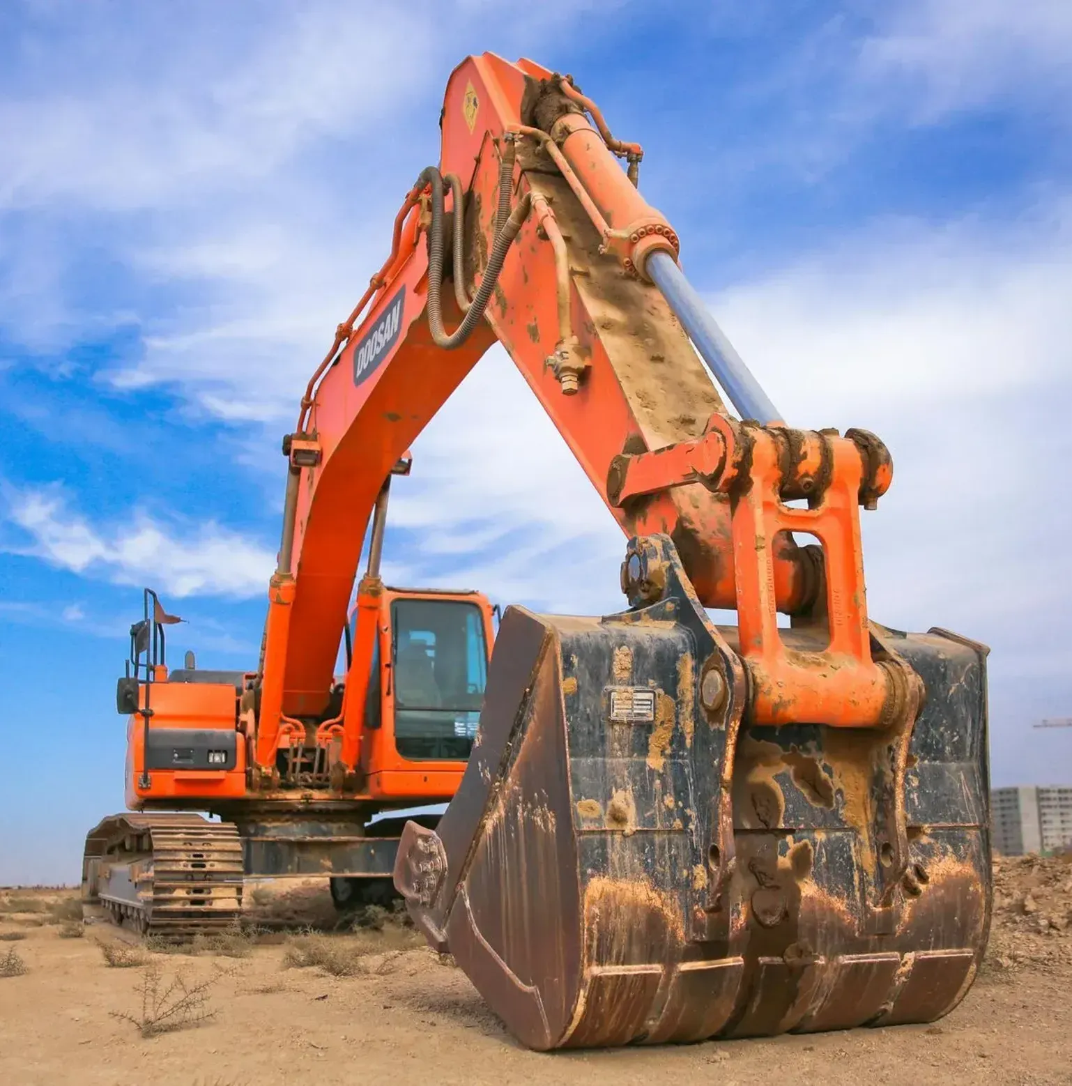 A large orange excavator is sitting on top of a dirt field.
