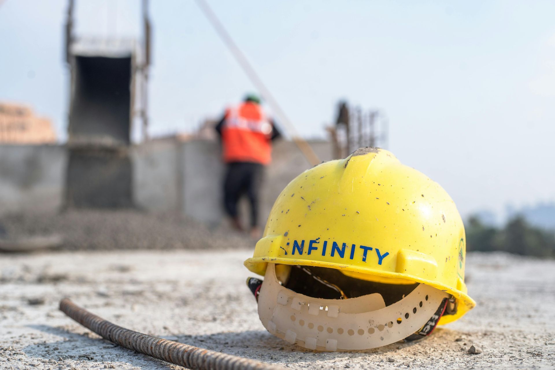 A yellow hard hat with the word infinity on it is laying on the ground.