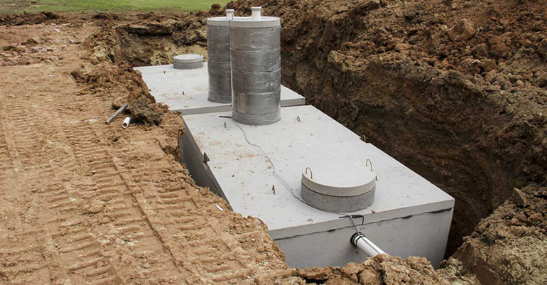 A septic tank is being built in a dirt field.