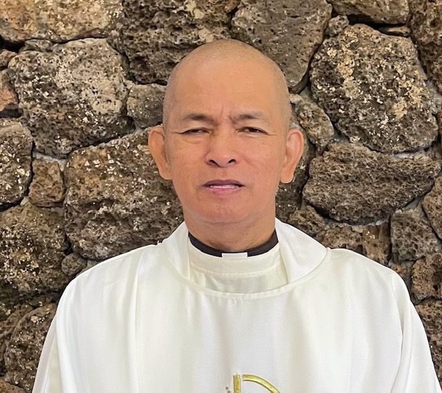 Photo of Fr. Francisco Sanchez in vestments standing in front of altar