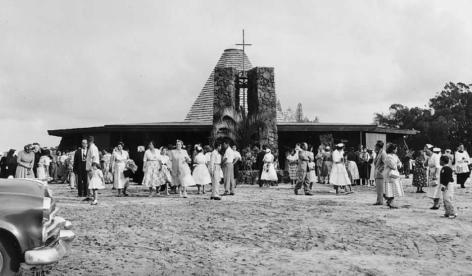 Black and white photo of new St. Sylvester church with many people talking in small groups in front of it