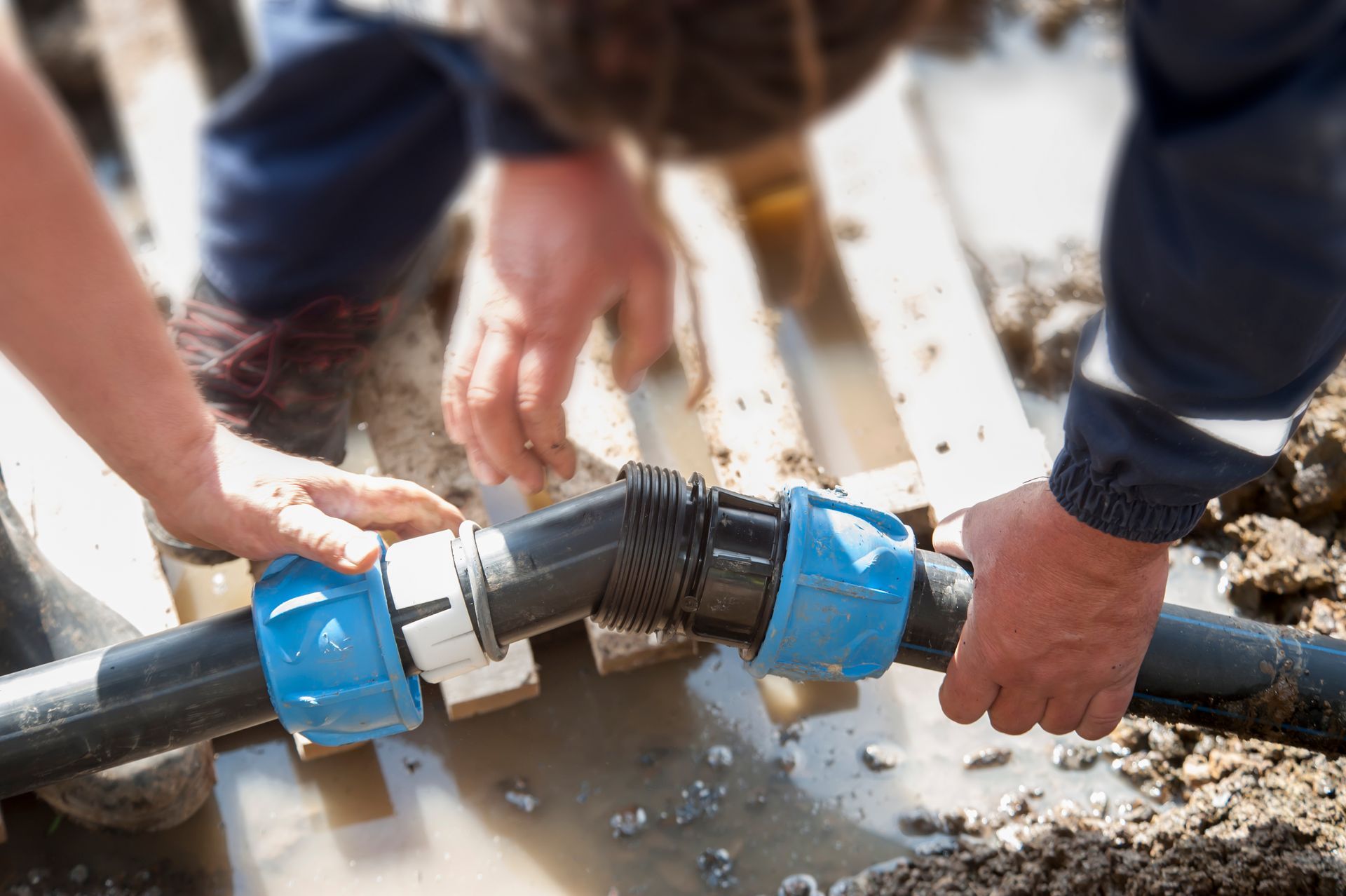 Two people connecting water pipes outdoors