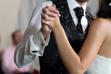 Two people dancing closely, with hands clasped at a formal event
