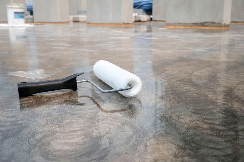 A Paint Roller Is Laying on A Concrete Floor — Fraser Coast Waterproofing in Pialba, QLD