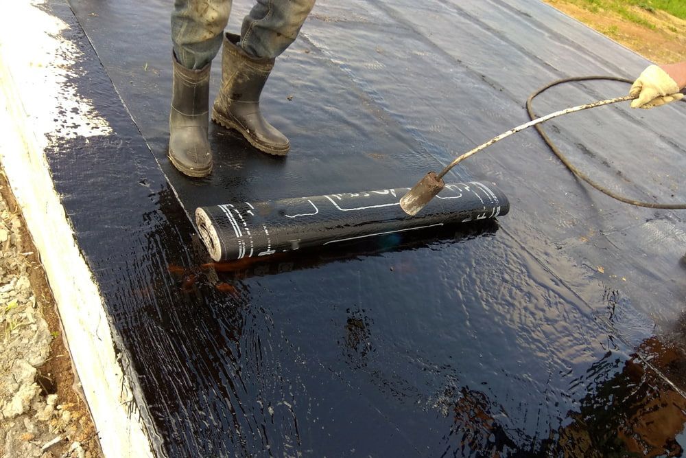 A Person Is Standing on A Roof with A Torch — Fraser Coast Waterproofing in Pialba, QLD