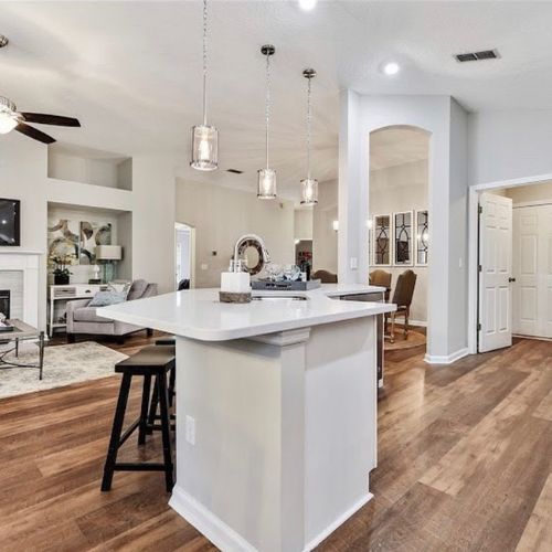 Open-concept kitchen with island and pendant lights. Hardwood floors and entry to living area. Open-concept kitchen with island and pendant lights. Hardwood floors and entry to living area.