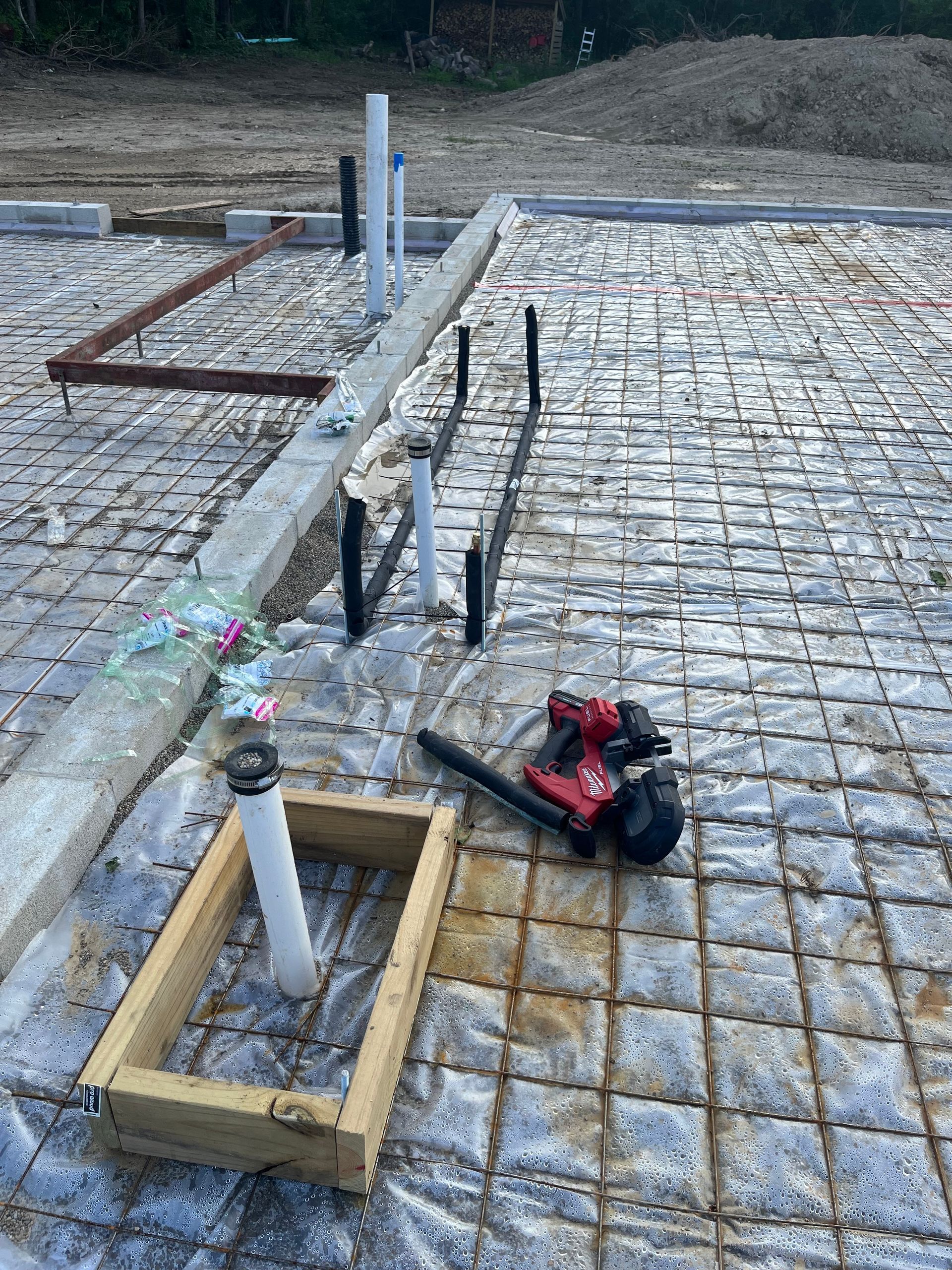 A drill and a wooden frame are laying on a concrete floor.