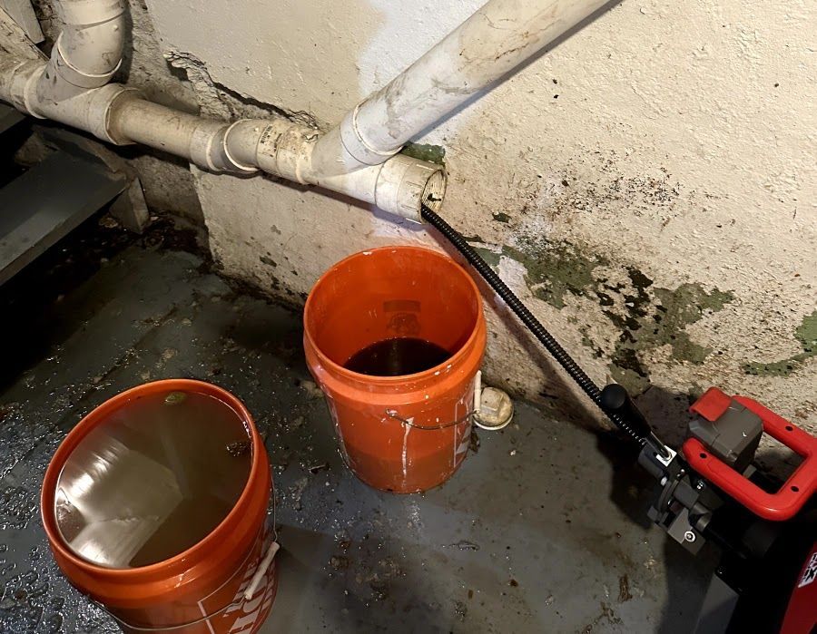 Two orange buckets filled with water next to a pipe