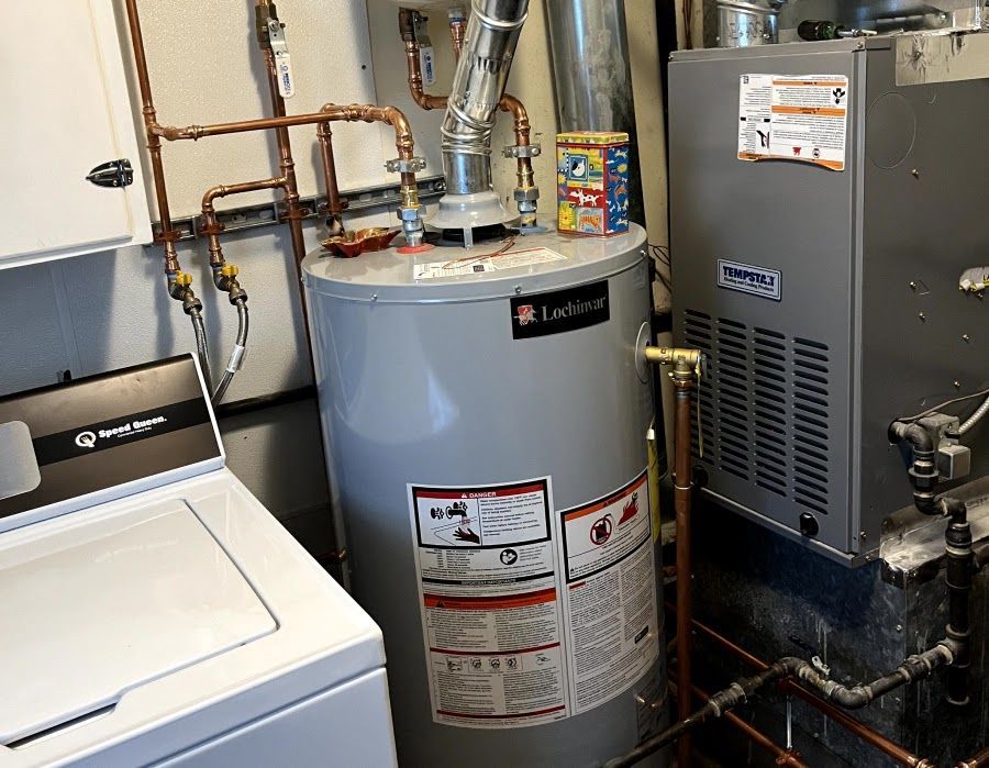 A water heater is sitting next to a washer and dryer in a laundry room.