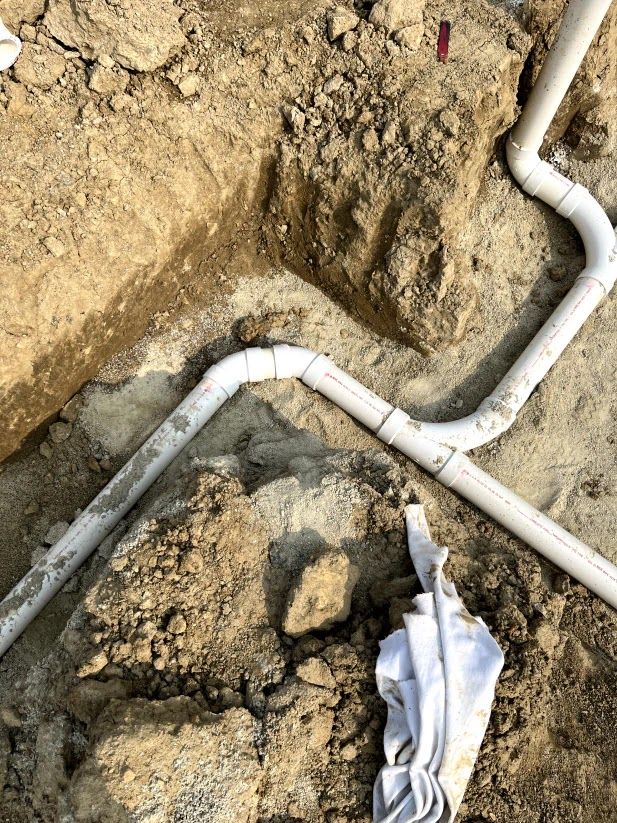 A bunch of pipes are laying in the dirt.