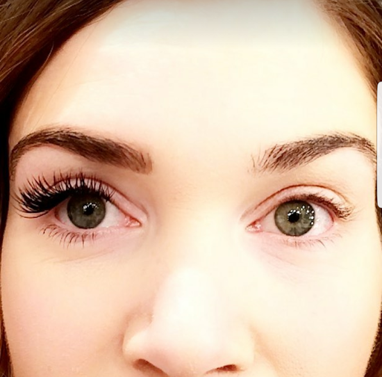 Woman's face, one eye with long, dark lashes, the other with natural lashes, showcasing eyelash extensions.