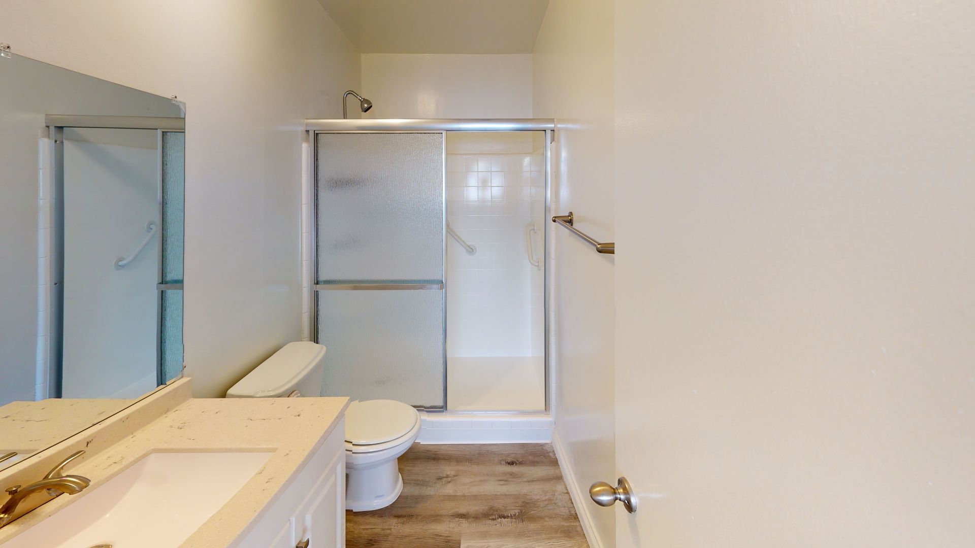 Bathroom with a white vanity, toilet, and a shower with sliding glass doors.