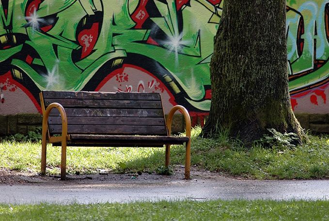 A park bench in front of a wall with graffiti on it