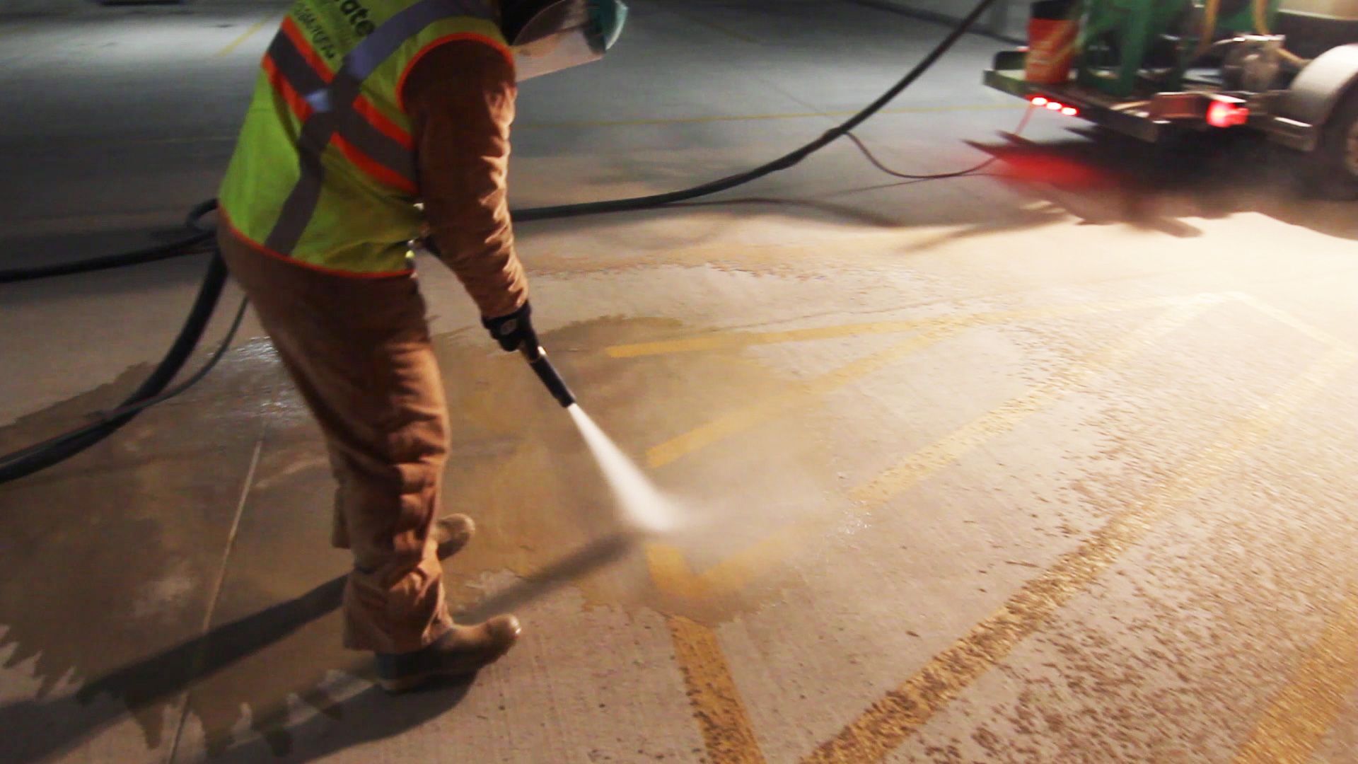 A man is using a high pressure washer to clean a concrete floor.