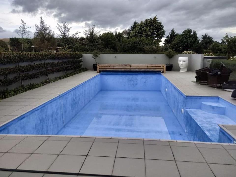 A large blue swimming pool with a bench in the background