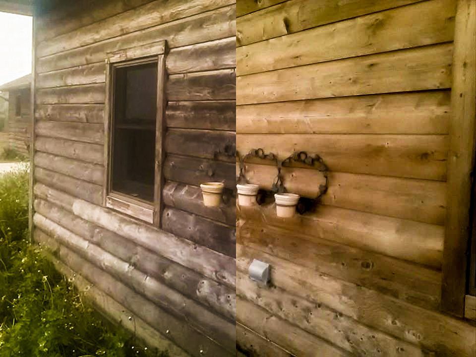 A log cabin with a window and pots on the side of it.