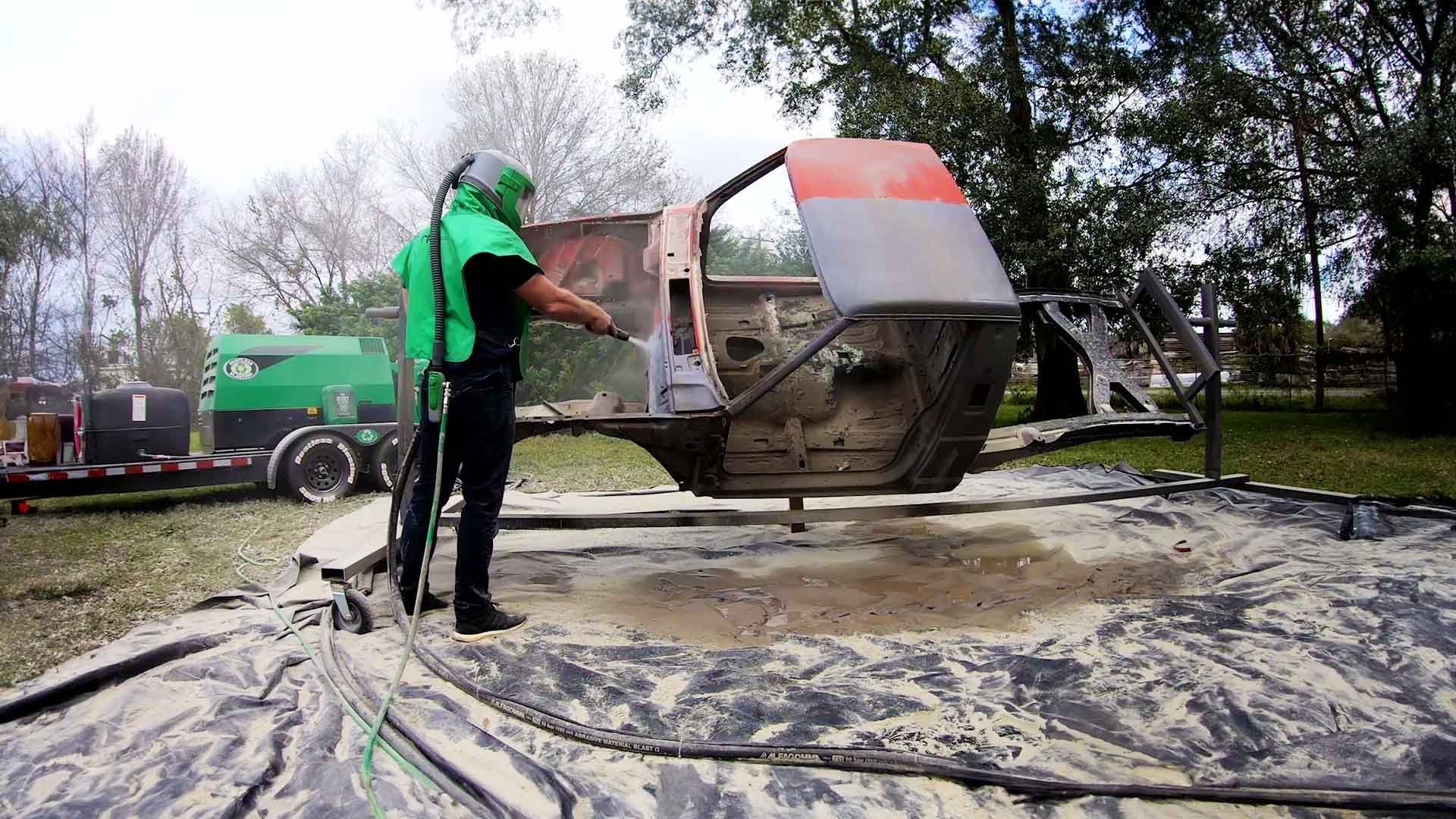 A green trash can is being cleaned with a high pressure washer.