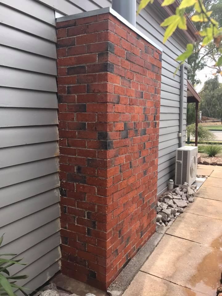 A large red brick chimney is on the side of a house.