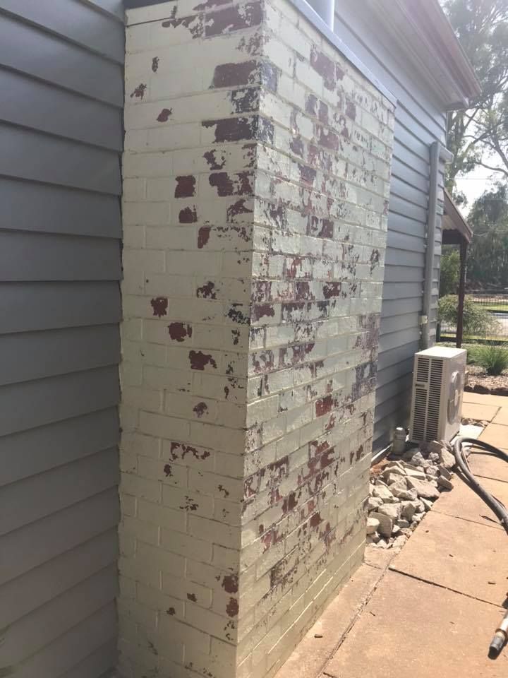 A brick wall with a chimney on the side of a house.