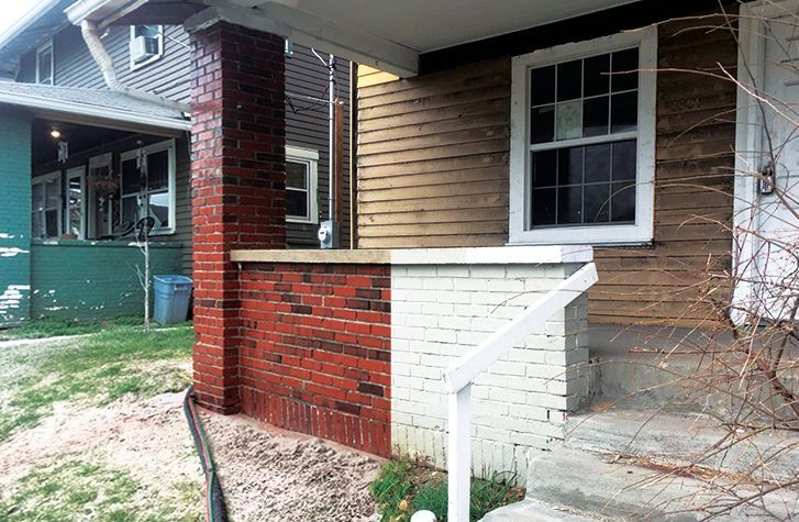 A house with a brick porch and a white railing.