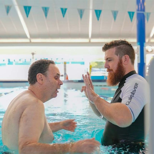 two men are giving each other a high five in a swimming pool .