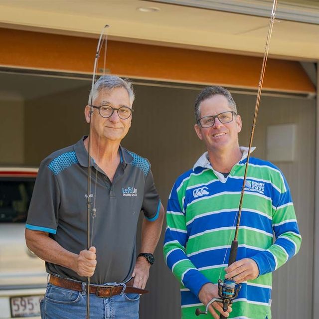 two men are holding fishing rods in front of a garage door .