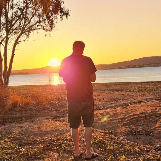 a man standing on a beach looking at the sunset
