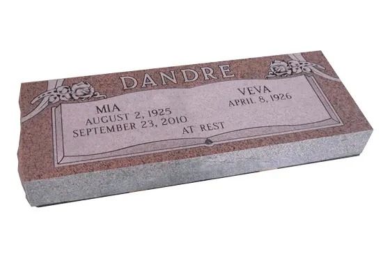 Pink and gray marble gravestone with engraved names and dates, shown at an angle.