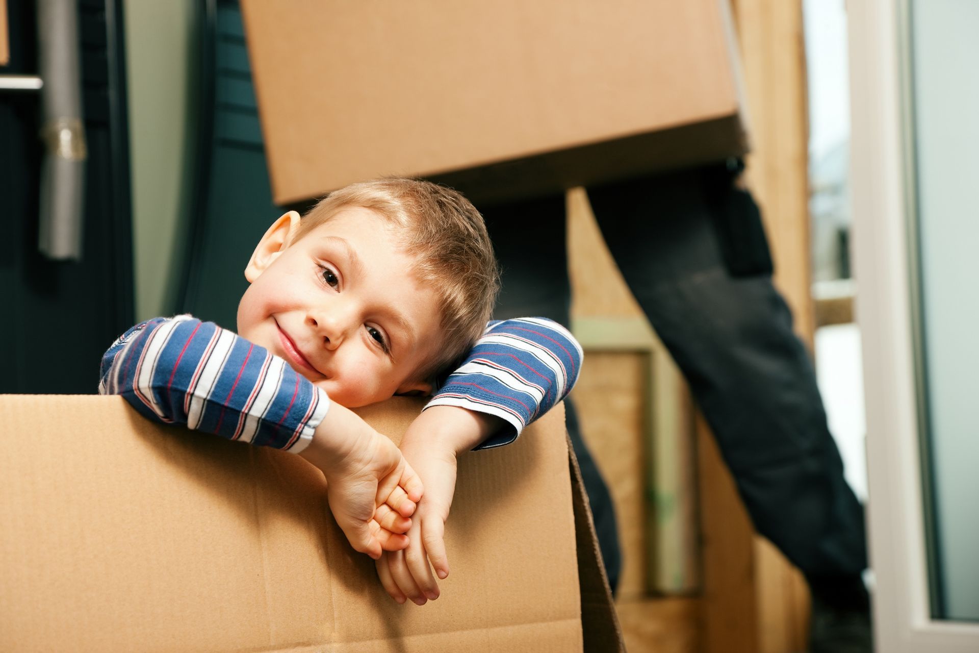 A young boy is sitting in a cardboard box.