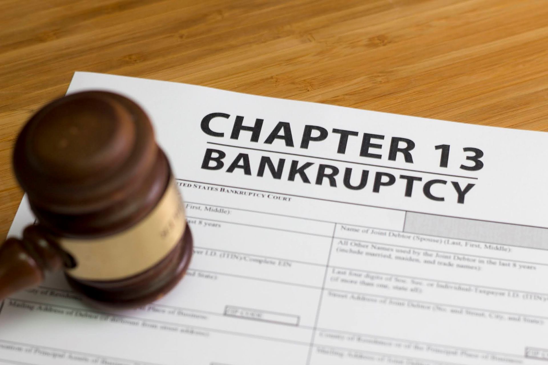 A wooden judge 's gavel is sitting on top of a chapter 13 bankruptcy form.