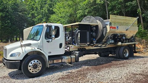 a large white truck is parked on a gravel road .