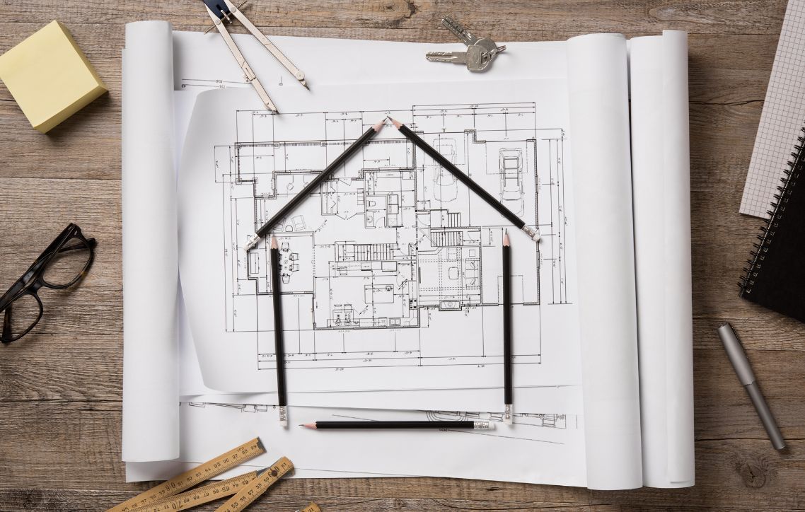 A black and white drawing of a house on a wooden table.