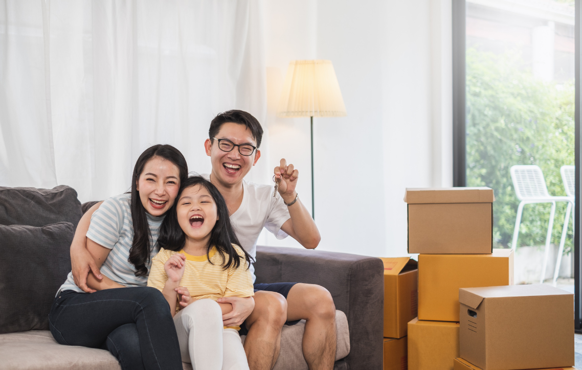 A family is sitting on a couch in a living room with boxes.