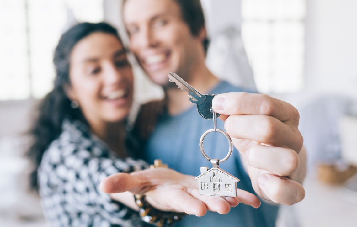 A man and a woman are holding keys to their new home.