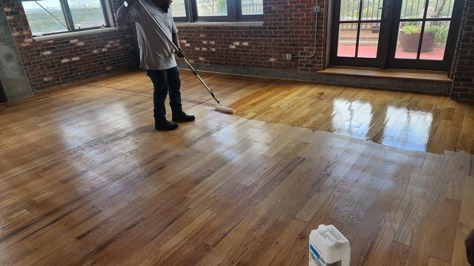 A person is cleaning a wooden floor with a mop.