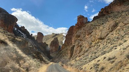 A dirt road in the middle of a canyon surrounded by rocks.