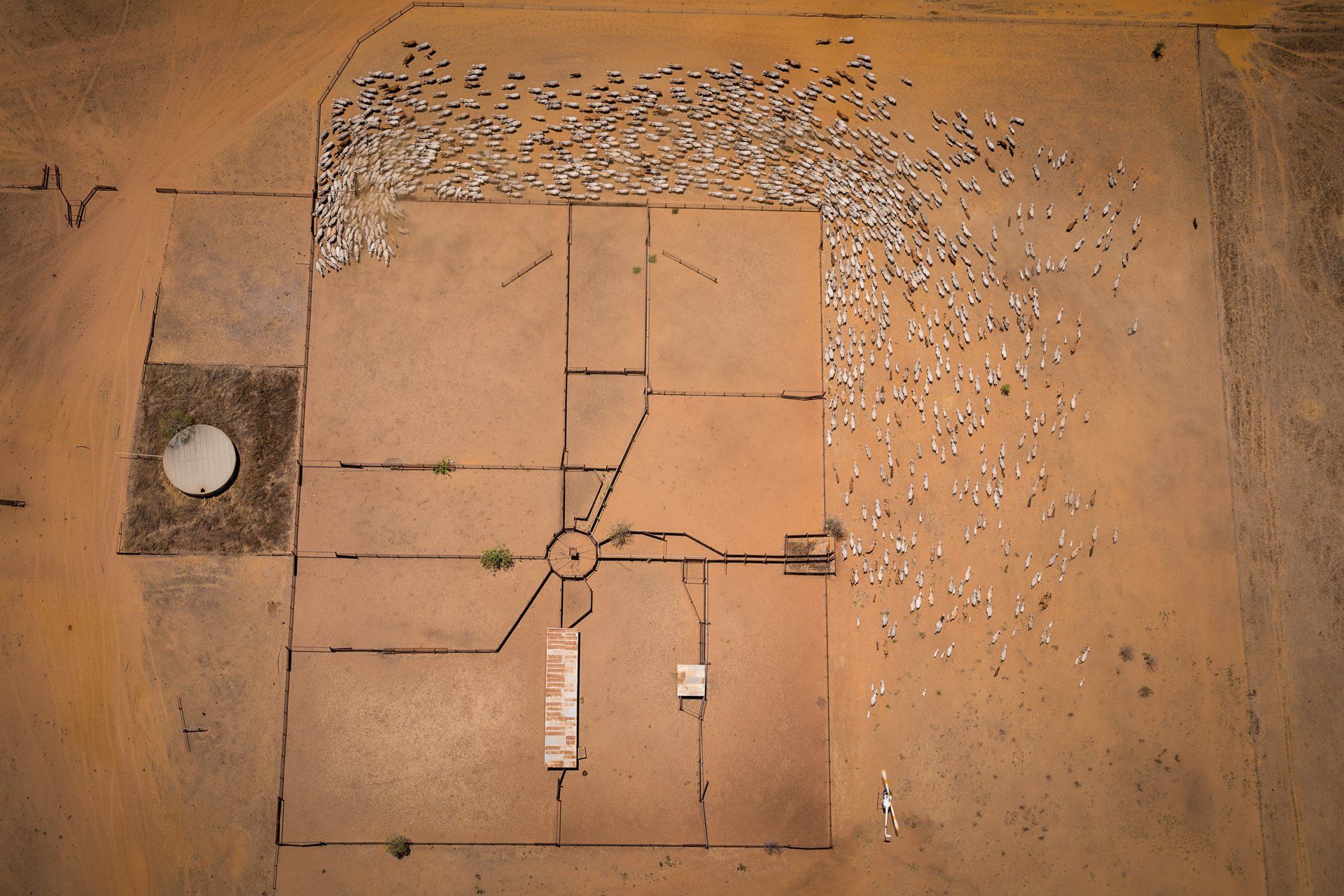Aerial view of a grid-like layout on brown land with a satellite dish and scattered light-colored debris.